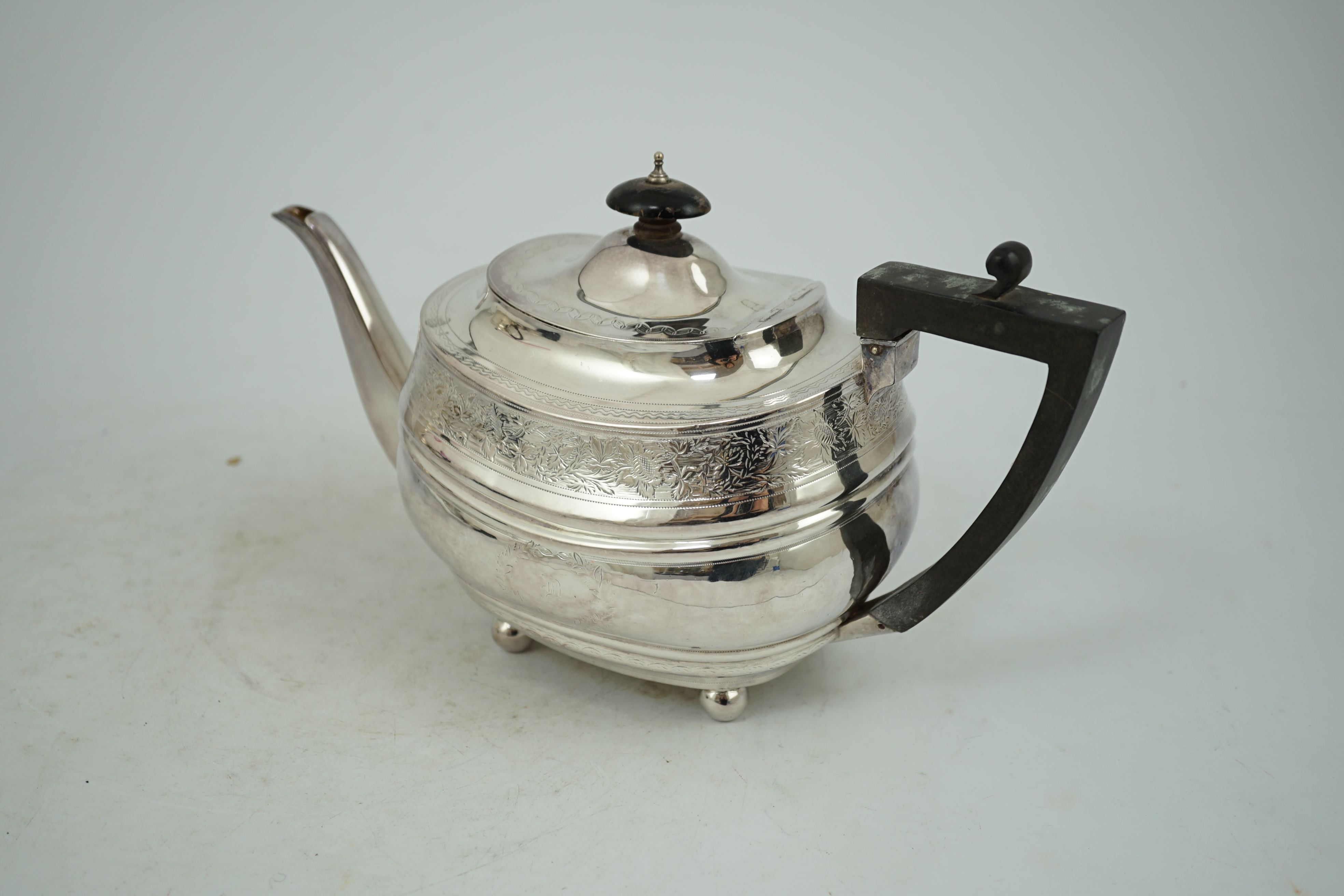 A George III engraved silver shaped oval teapot, on ball feet, Thomas Wallis II, London, 1807, gross weight 16.1oz.